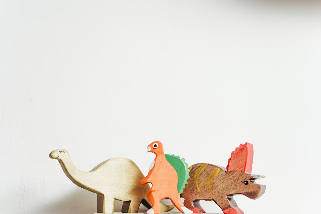 about-us-02 Three wooden dinosaur toys on a white background showcasing playful creativity.