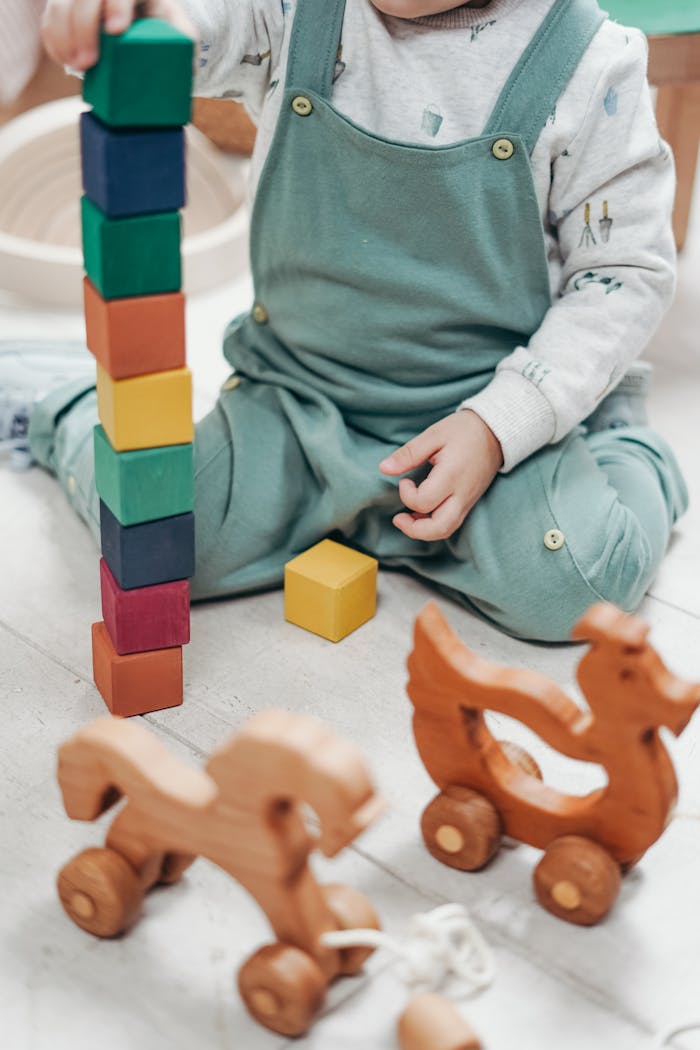 about-us-02 A child enjoying playtime indoors with colorful wooden blocks and toys.